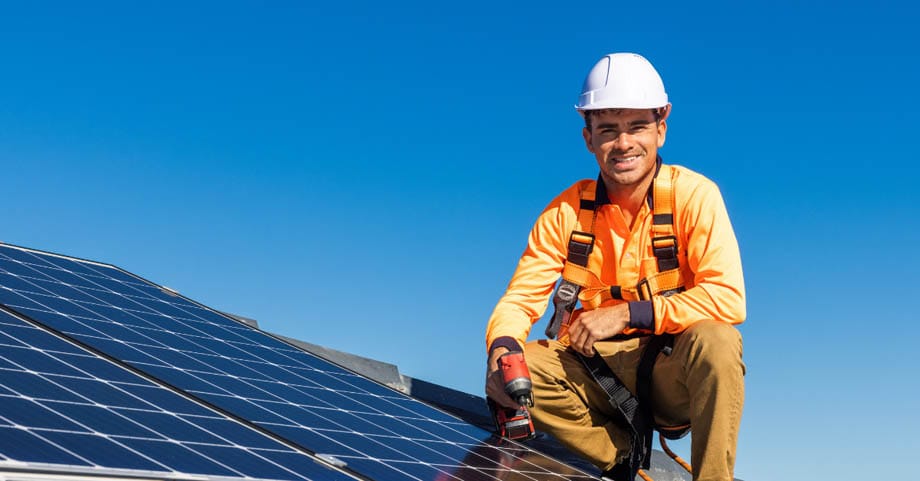 Serviser v varnostni opremi popravlja sončno elektrarno na strehi