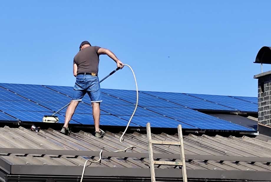 sam ocistil soncno elektrarno Lastnik čisti sončne panele na strehi z deževnico.